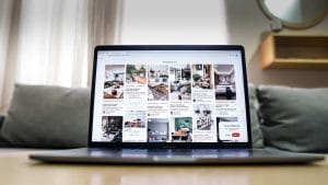 A laptop with pictures on it is being utilized in a living room for implementing Pinterest to promote a blog.