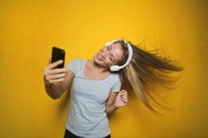 A young woman is taking a selfie against a yellow background, showcasing the best ways to make money for free online.